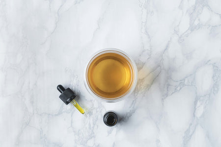 CBD oil next to a glass of whisky