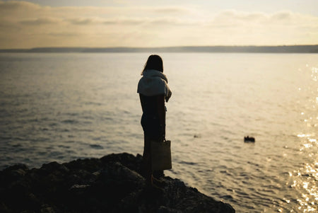 A woman stood on a cliff looking at the sea