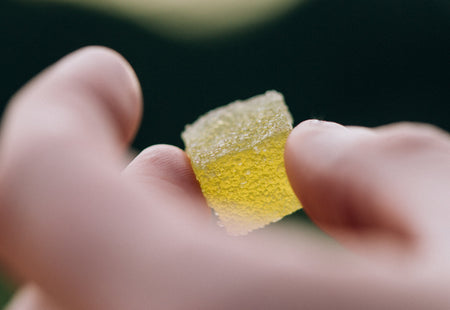 A yellow gummy being held up by a hand